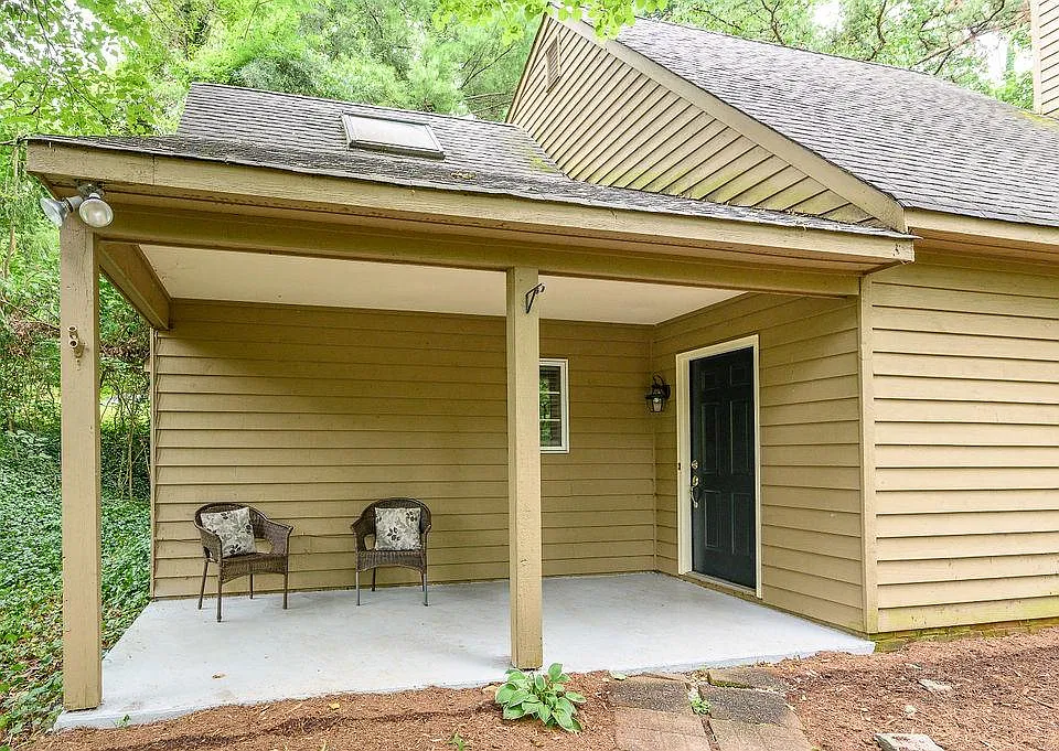Large lounging front porch. House surrounded by trees for a lovely, secluded feeling.