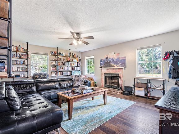 Living room with a textured ceiling, plenty of natural light, dark hardwood / wood-style floors, and a brick fireplace