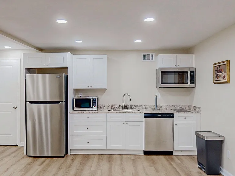 Streamlined kitchen with stainless appliances, ample shaker cabinetry, granite-look counters, and a double-basin sink.