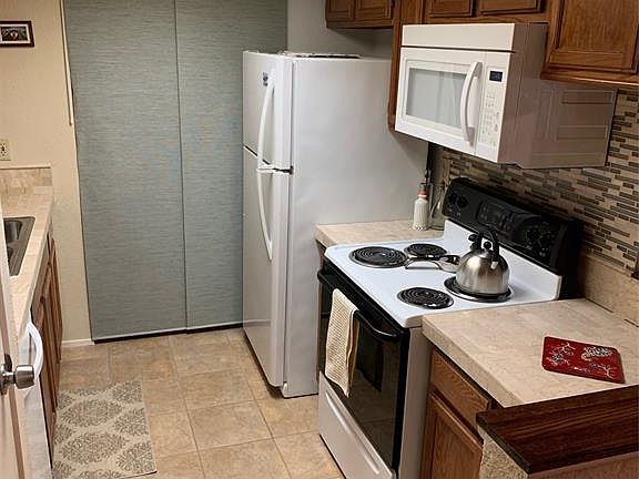 This view of the kitchen is taken from the formal dining area. The kitchen was recently updated with tile counters and colorful/ decorative back splash for a clean look! The space behind the closed off area is the washer/dryer.