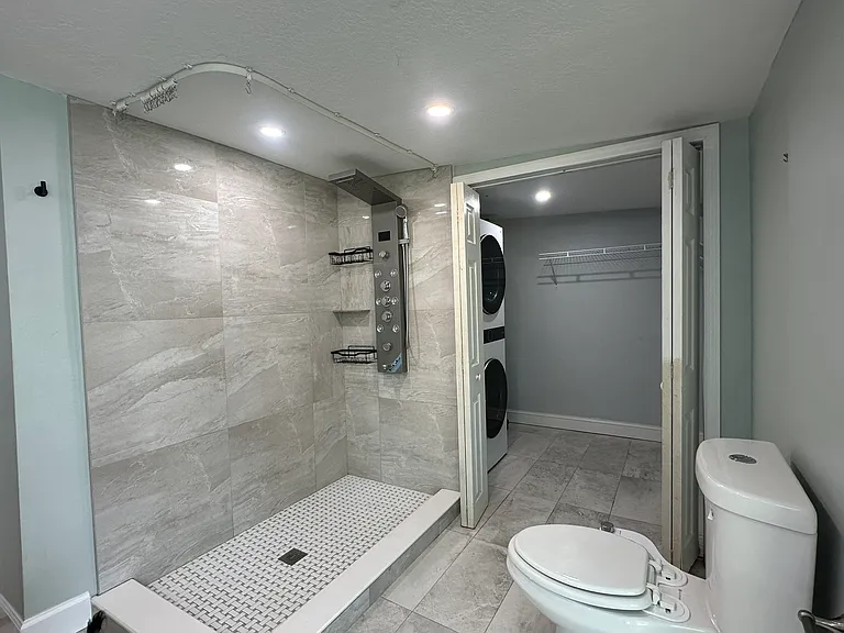 master bathroom spa shower and walk in closet with washer / dryer
