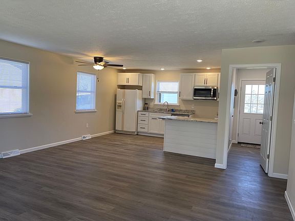 Kitchen with room for bar stools and table. View going into utility and out back door.
