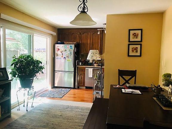 View from the dining area into the kitchen. The carpet will be replaced with all new flooring. Sliding door to outdoor patio