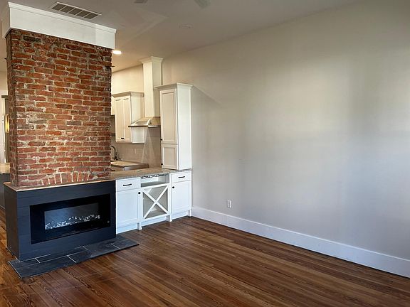 Living area with electric fireplace and original wood floors