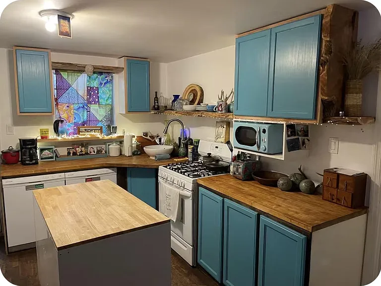 Functional kitchen with ample cabinetry, butcher block counters, and a central prep island for extra workspace.