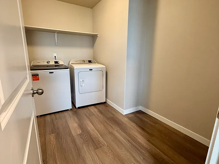 Convenient laundry room with overhead shelf.