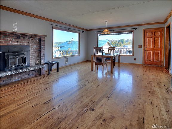 Open concept great room features crown molding, wood burning fireplace insert, hardwood floors, access to the partially covered upper deck and views of Puget Sound and the Narrows bridge. 