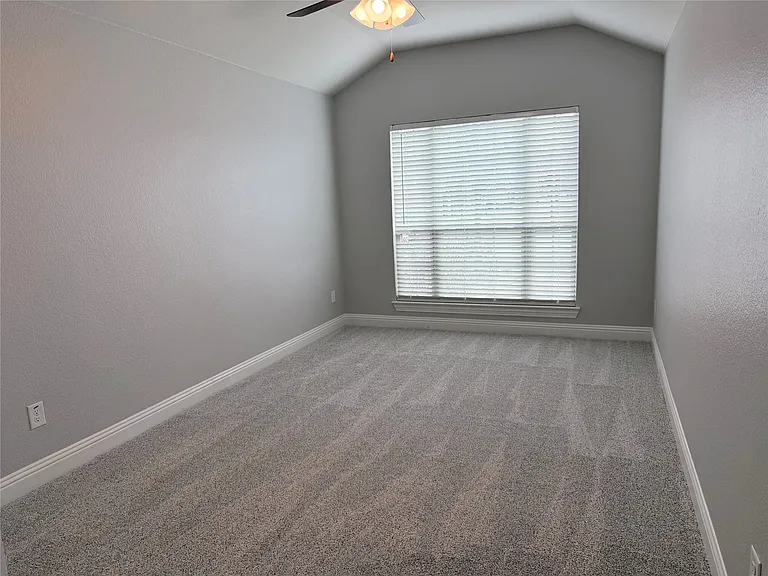 This spacious and light-filled primary bedroom features neutral paint tones, plush carpeting, and large windows that provide abundant natural light, creating a serene and inviting retreat perfect for relaxation.