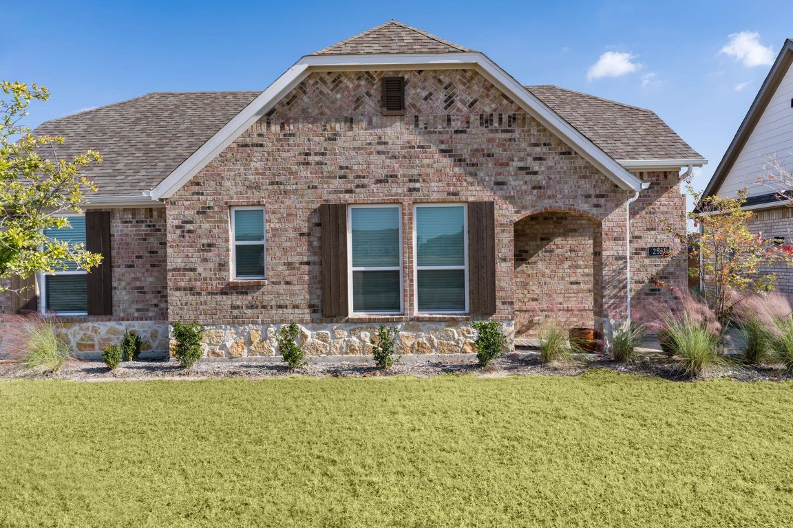 A charming cottage at Amavi Celina featuring brick detailing, a private front entry, and a landscaped yard that adds curb appeal.