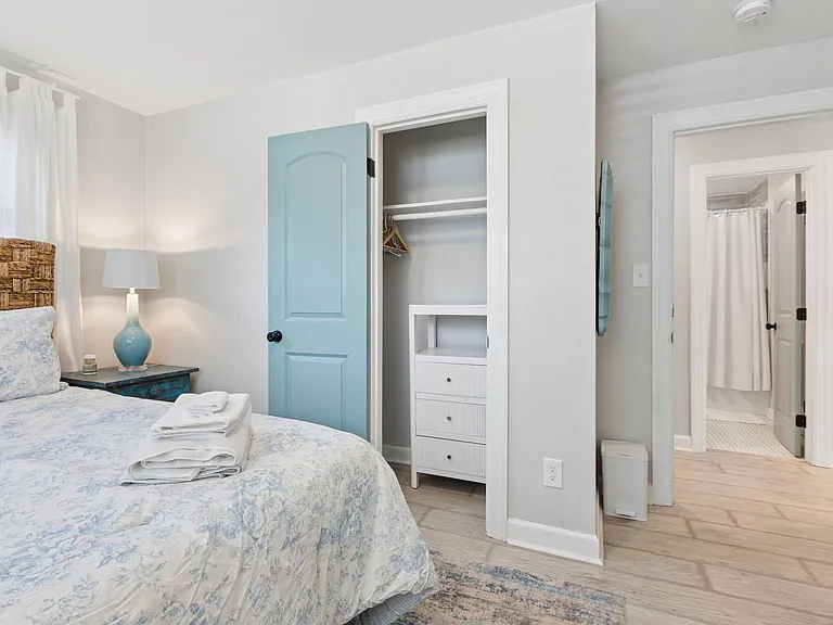Furnished bedroom with a bedside table, sizable closet storage, and quick access to a nearby full bathroom.