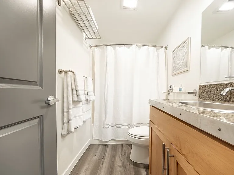 Bathroom with tub / shower combo, water resistant flooring and under sink storage