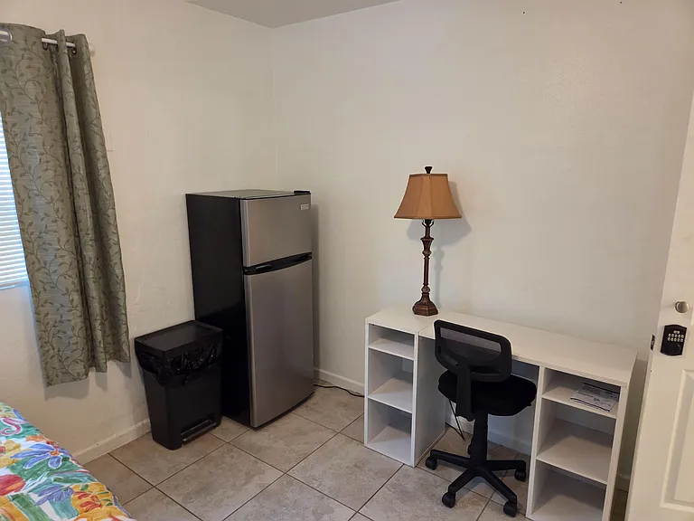 Private bedroom area with a dedicated work desk, shelving, and in-room 7.5 cu ft fridge for added convenience.