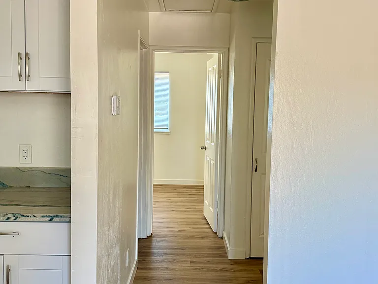 Hallway leading to 1 bathroom and 2 bedrooms