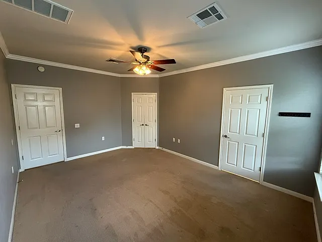 View of master bedroom from back corner. Right door leads to large walk-in closet. Double doors lead to master bathroom. Left door leads to hall/laundry room.