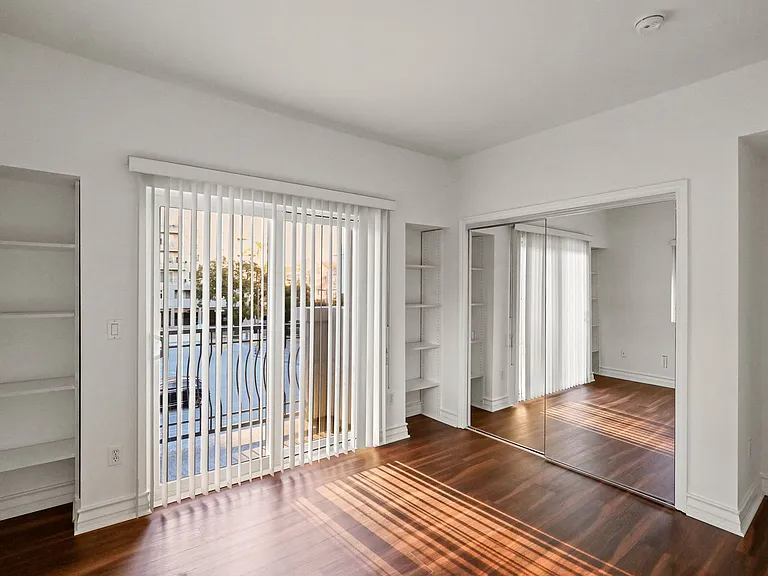 Bedroom with Mirrored Closet, Built-In Shelving, and Balcony