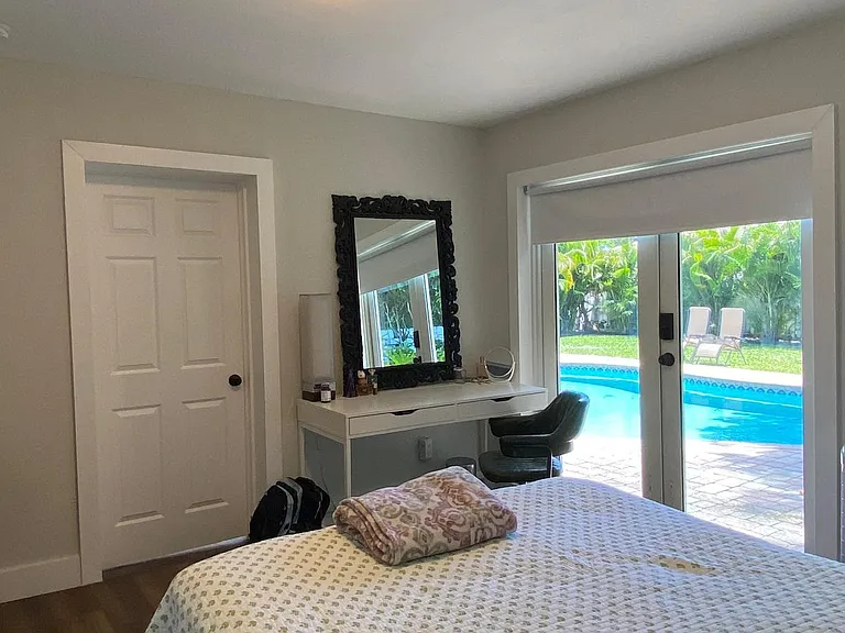 Bedroom with a dedicated vanity area and large sliding glass doors opening to a poolside patio.
