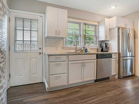 Kitchen sink looks out onto fenced patio and grape arbor.