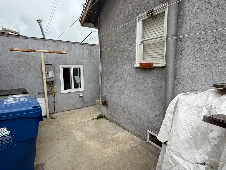 Side patio area with clothesline. Window of available room pictured on right hand side of photo. Washer/dryer hookups in garage pictured slightly left of straight ahead.