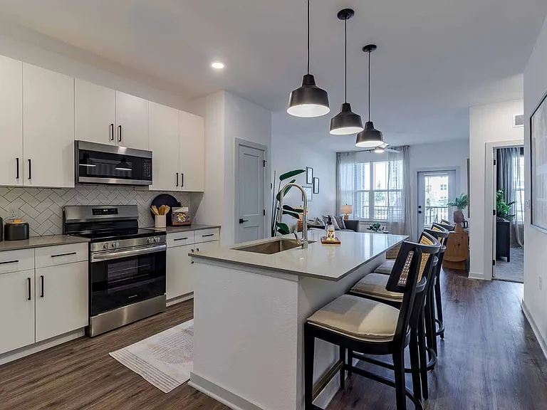 Open-concept kitchen with a quartz island, stainless steel appliances, and herringbone tile backsplash. Open-concept kitchen with a quartz island, stainless steel appliances, and herringbone tile backsplash.