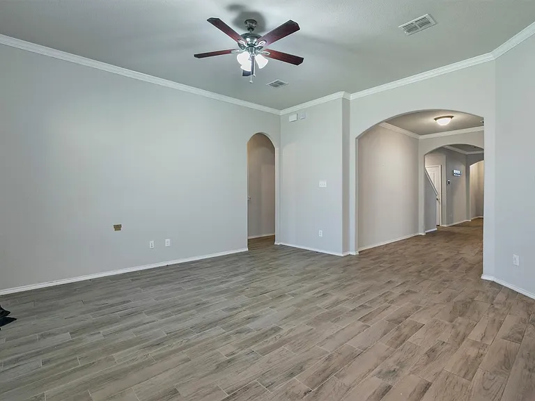 Spacious interior with wood-finish flooring, vaulted ceilings, a ceiling fan, and arched doorways
