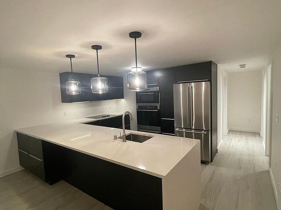 Spacious modern kitchen with built in appliances, quartz waterfall counter, under counter lighting