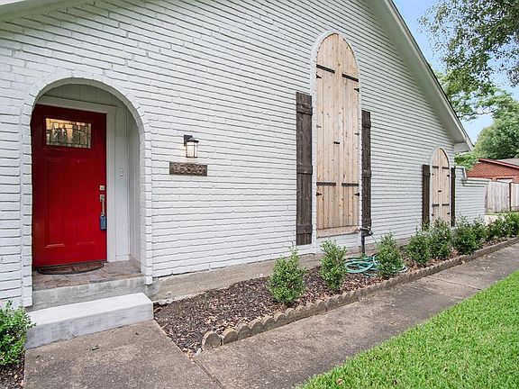 The red front door adds quite an accent to this white painted brick home.