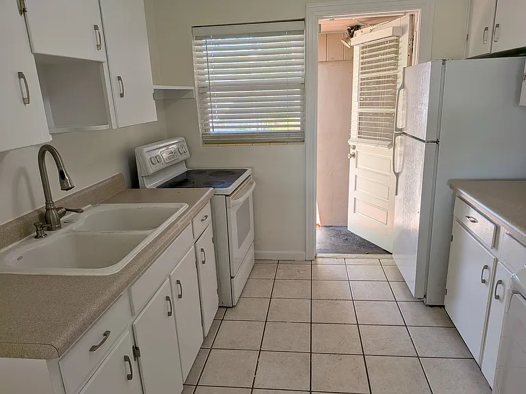 The kitchen has a rear door to the back yard and exterior utility closet. The apartment shares a small breezeway with the other apartment.