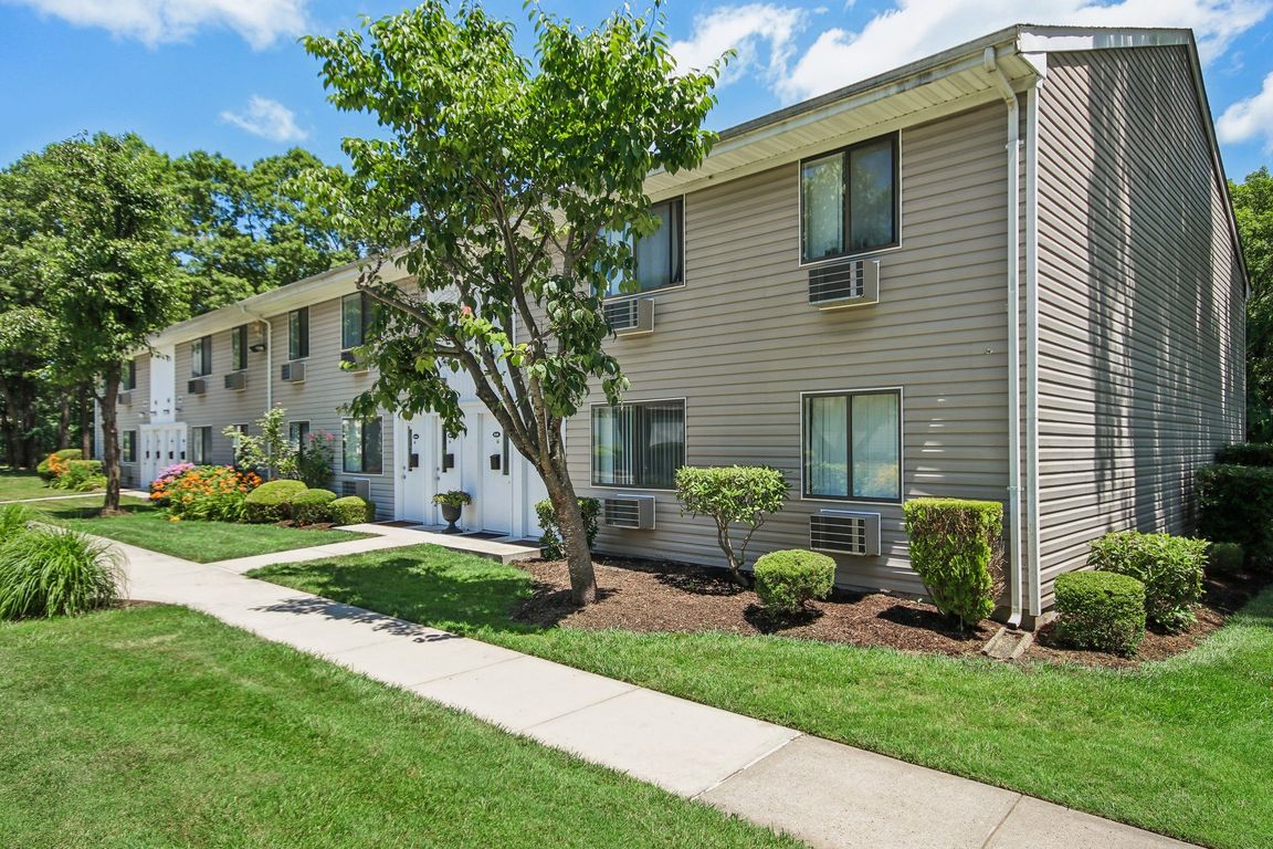 Outside view of apartment with a sidewalk and trees in front