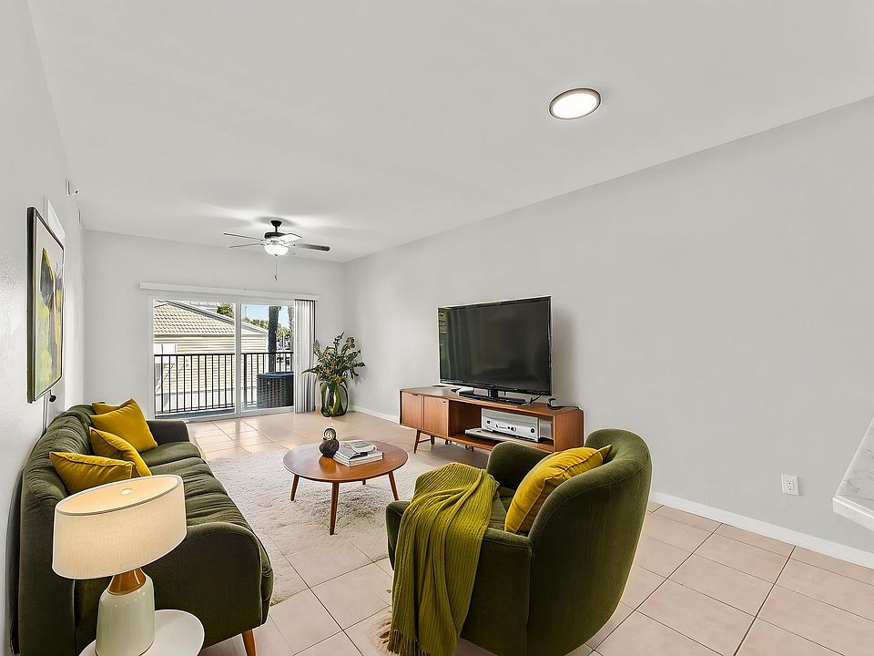 Inviting modern living room with plush green furniture, sleek wooden media console, and expansive sliding glass doors leading to a balcony view.