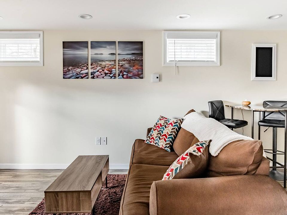 The lower level features a spacious, fully furnished living room designed for comfort and relaxation, complete with modern decor and direct walkout access, seamlessly connecting indoor comfort with outdoor convenience.