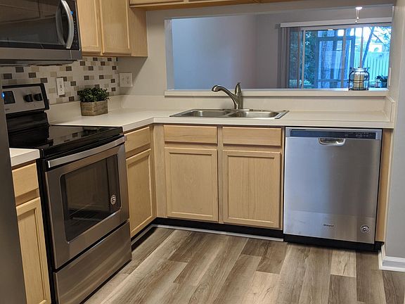 kitchen with never used SS appliances and new laminate flooring and tile backsplash
