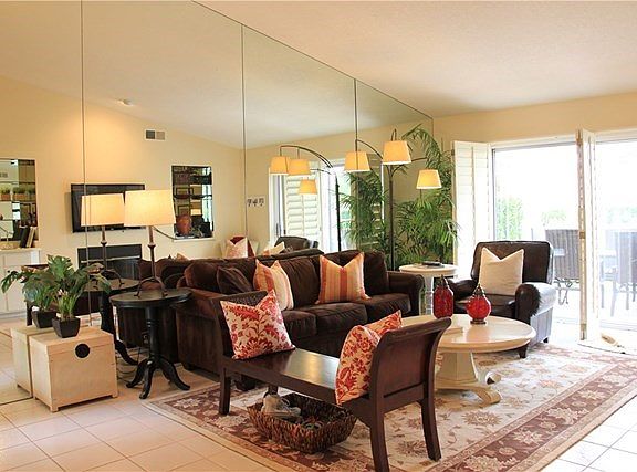 Light and bright family room with neutral tile floors and walls of windows overlooking the patio and