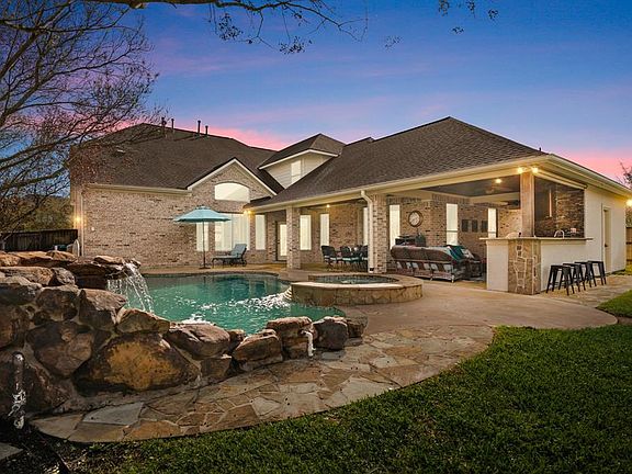 Incredible backyard resort oasis, which is perfect for entertaining and relaxing at home, with a large covered patio and outdoor kitchen, raised spa, sparkling pool with rock waterfall and pool half bathroom.
