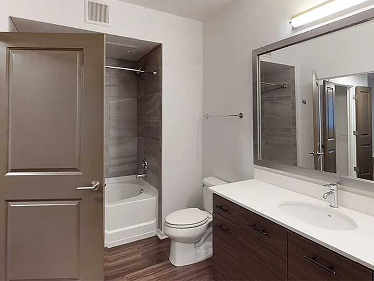 Apartment bathroom with large soaking tub and wood-style flooring.