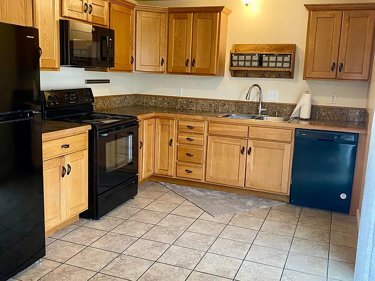 Large kitchen new refrigerator, granite countertops and tile floor.