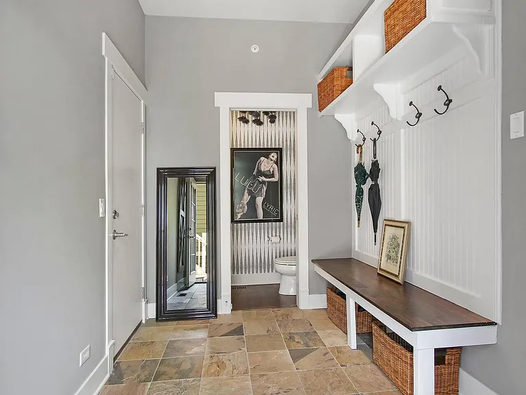 Generous mudroom between garage and main room with exterior side entrance leading to gas grill.