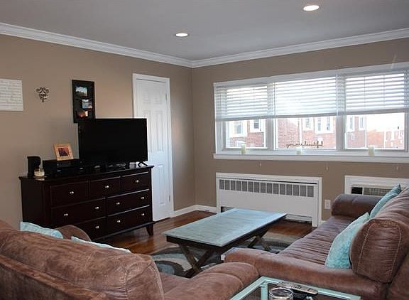Sun filling living room with hardwood floors and crown molding.