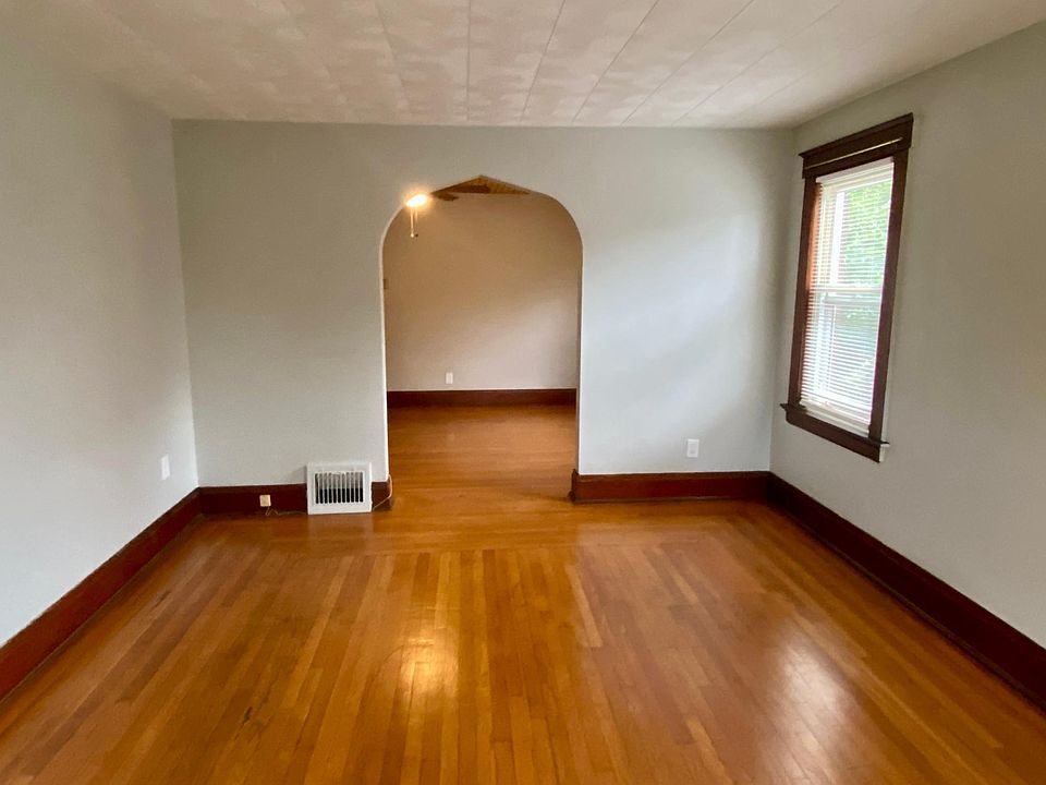 Large living room with plenty of natural light and beautiful hardwood flooring; looking into the dining room