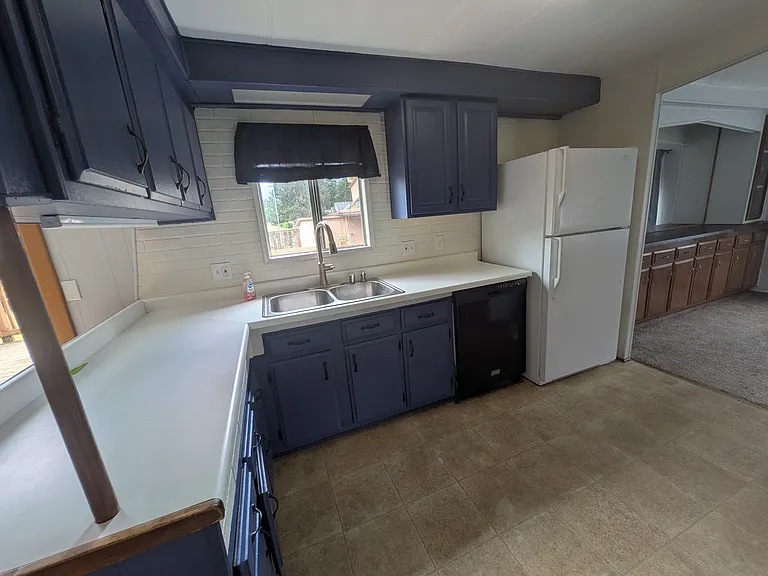 Kitchen facing sink, dishwasher, and refrigerator. Looks out to backyard. Dining room area to right.
