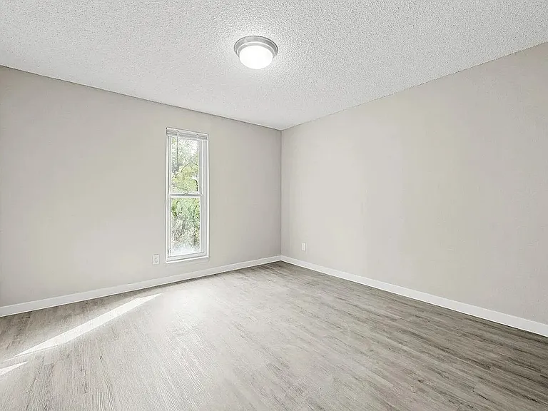 Bright, spacious living area with elegant hardwood floors and large sliding glass doors leading to a private patio.
