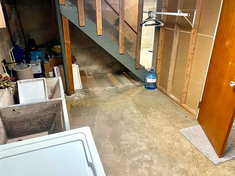 Laundry room with storage under stairs and clothing rack