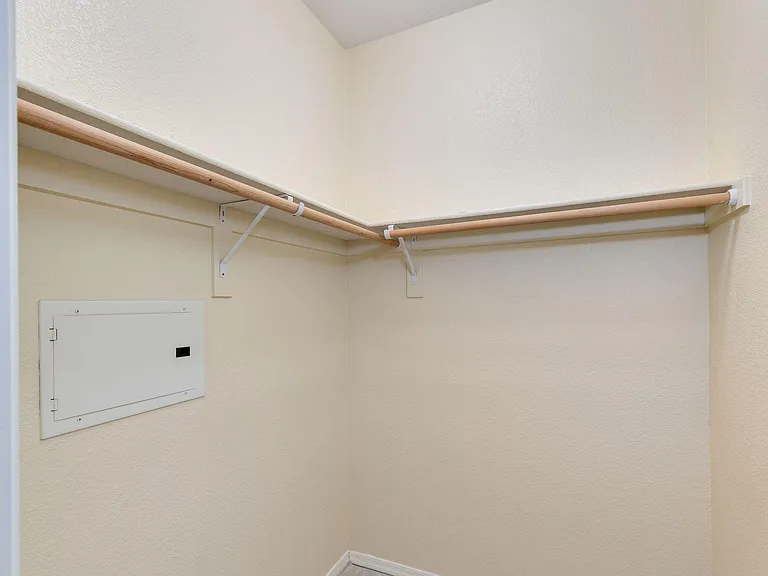 Walk-in closet with wraparound hanging rods and high shelf storage for easy organization of clothes and accessories.