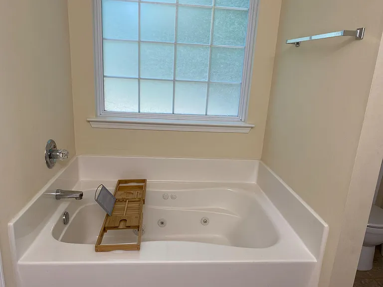 Oversized corner soaking tub with built-in jets and a frosted window for privacy and natural light.