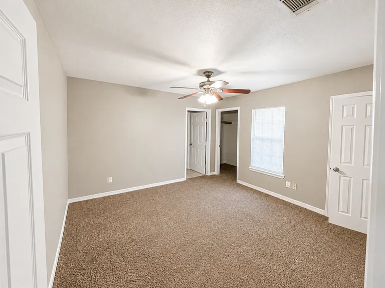 Jack & Jill Suite 1 _ Spacious bedroom with soft carpeting, abundant natural light, a ceiling fan, and two closets for exceptional storage. Connected to the shared Jack & Jill bathroom, offering comfort, privacy, and plenty of room to relax or study