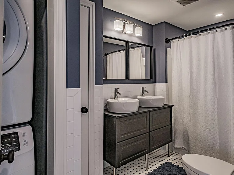 Newly renovated bathroom with double vanity and Samsung washer and dryer