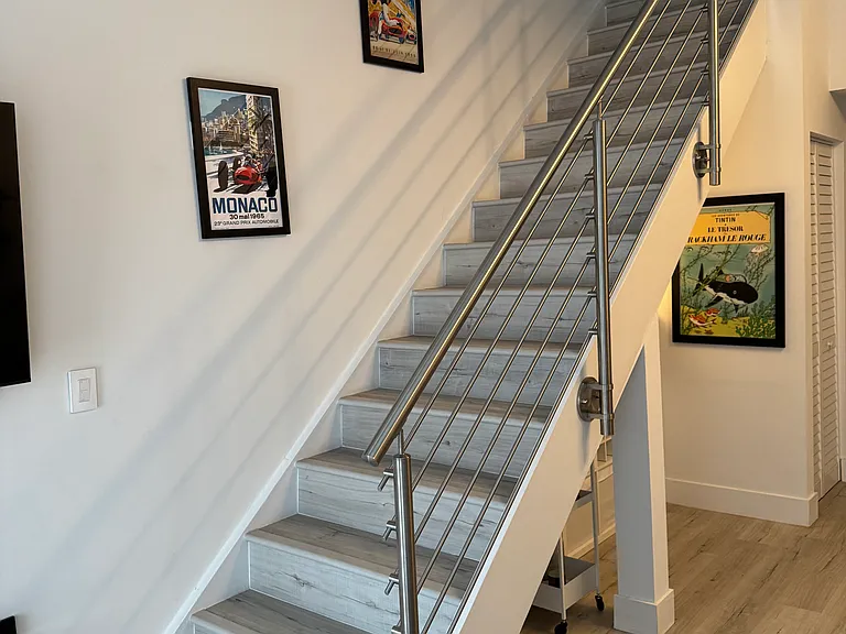 Staircase - Modernized stairwell with clean lines and updated finishes, serving as both a functional element and an architectural focal point providing separation and privacy from living area.