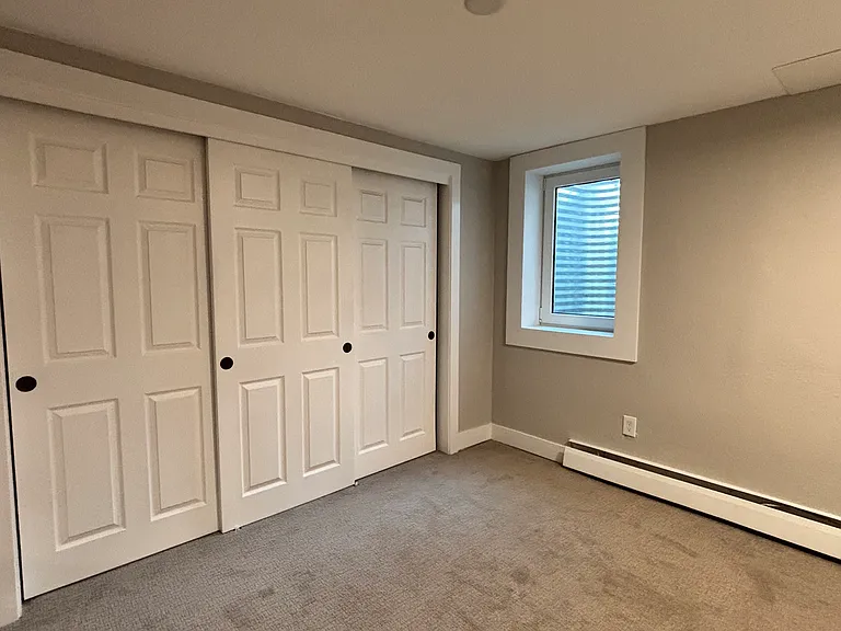 First bedroom. Well-lit area with wall-to-wall closet and modern decor.