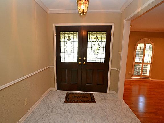 Entry with double beveled glass front doors, crown molding, chair rails and marble tile flooring.