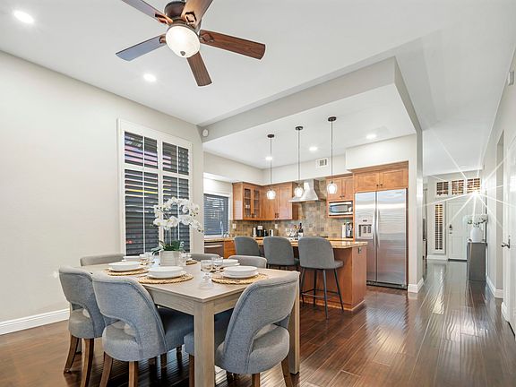 The dining room comfortably seats six and features a sliding door that opens to the backyard for easy outdoor access. A kitchen island with three barstools provides extra seating, making it ideal for both formal meals and casual gatherings.