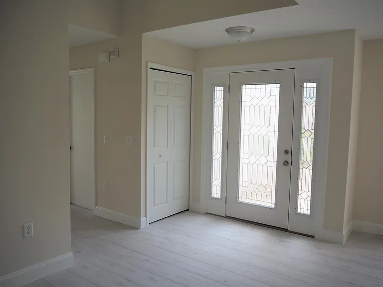 Bright sunny foyer with coat closet. Looking toward short hall that leads to garage, first floor office, formal living room or bedroom and half bath.